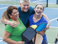 Smiling pickleball players hugging after a match